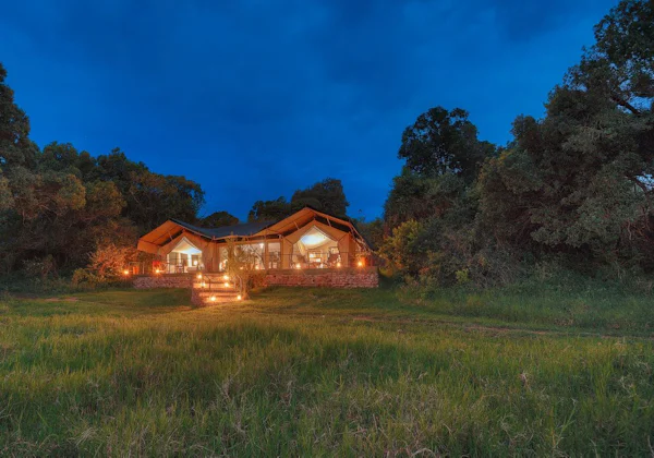 A safari camp glowing at dusk in the Mara North Conservancy, Kenya