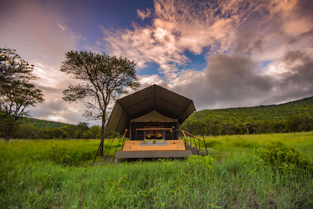 A tented safari camp set in the green central Serengeti below low hills, Tanzania