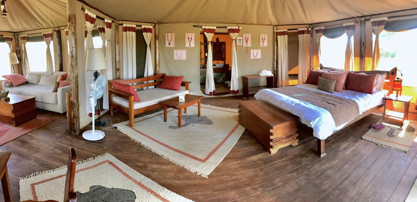 Spacious guest tent with a bed and a seating area at Elephant Bedroom Camp