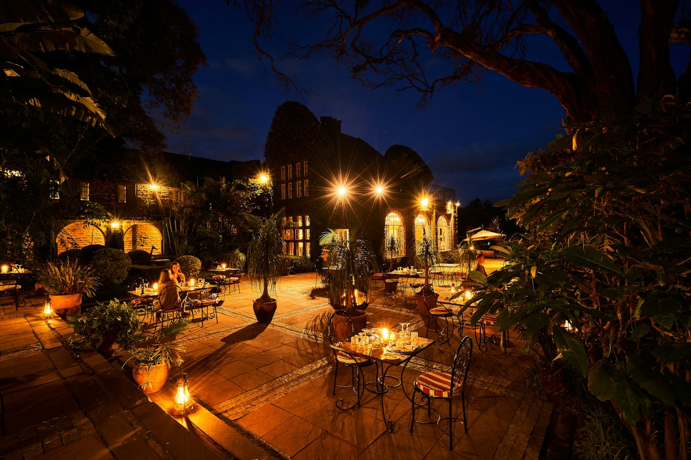 Garden dining tables illuminated at night at Giraffe Manor