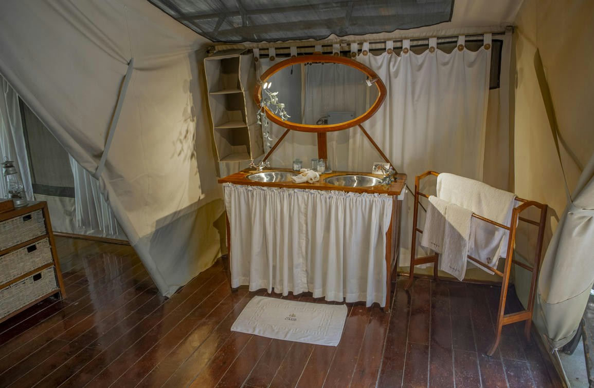 Guest tent bathroom with a basin and mirror at Karen Blixen Camp