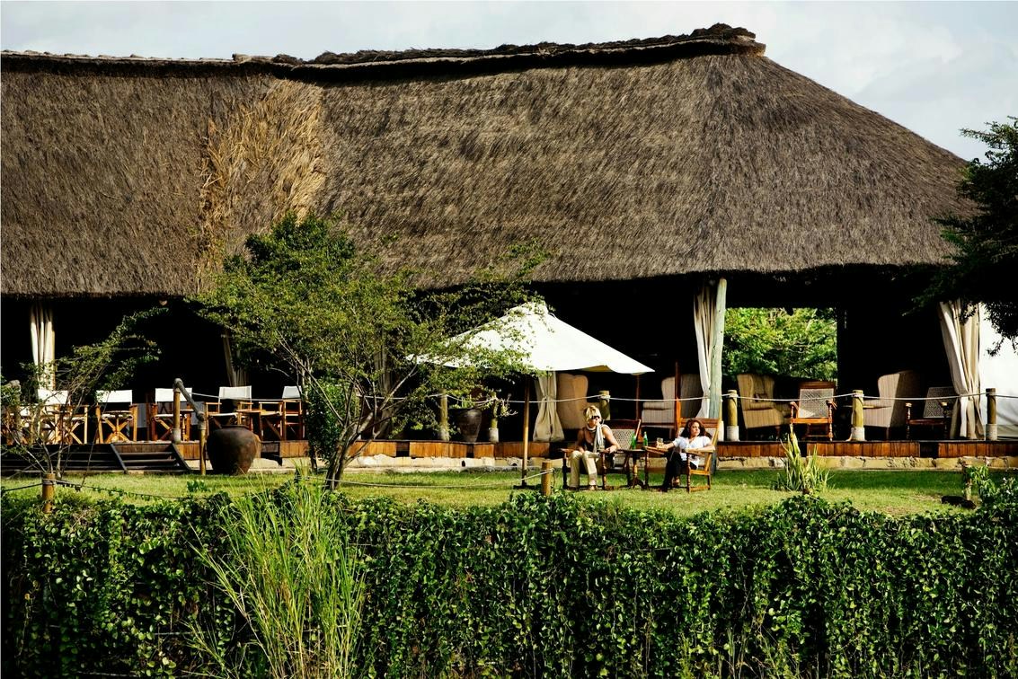 Thatched main area and shaded garden seating at Karen Blixen Camp