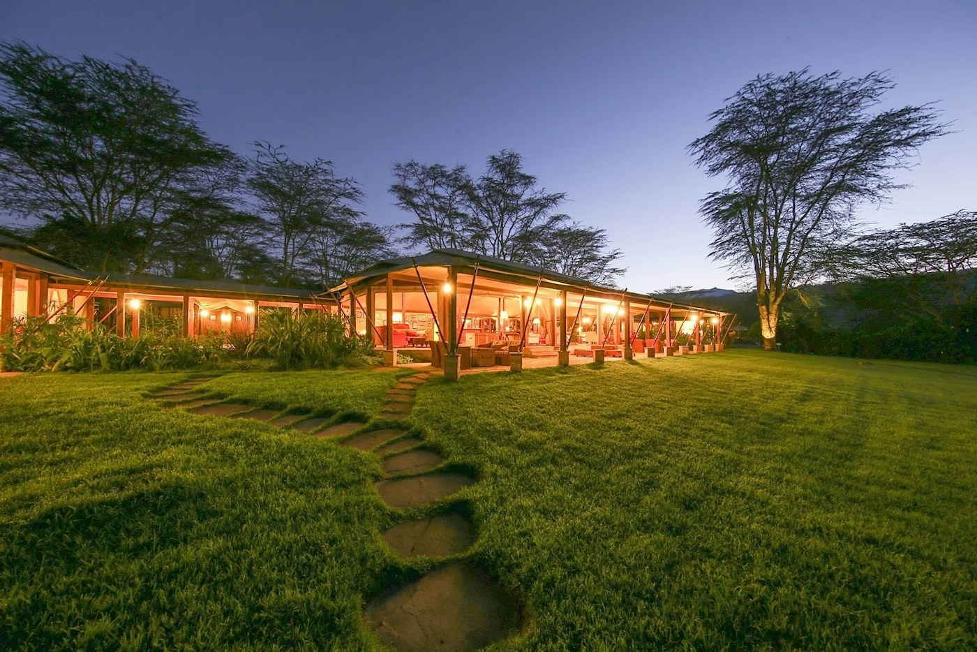 Camp grounds and illuminated main tents at dusk at Lake Elmenteita Serena Camp