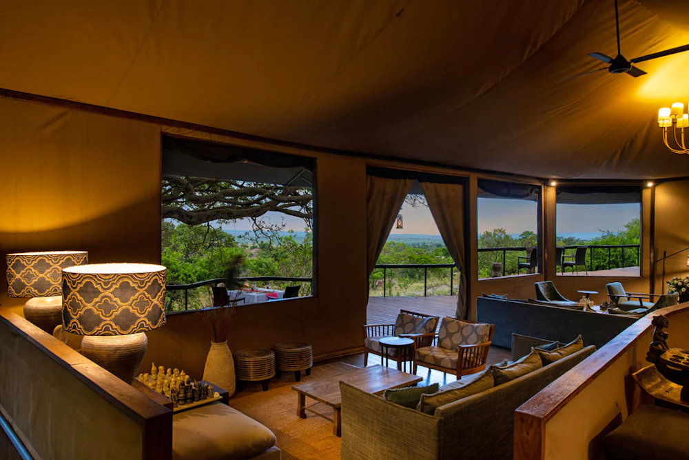 A warmly lit tented lounge with views over the Serengeti at dusk, Lemala Kuria Hills, Tanzania