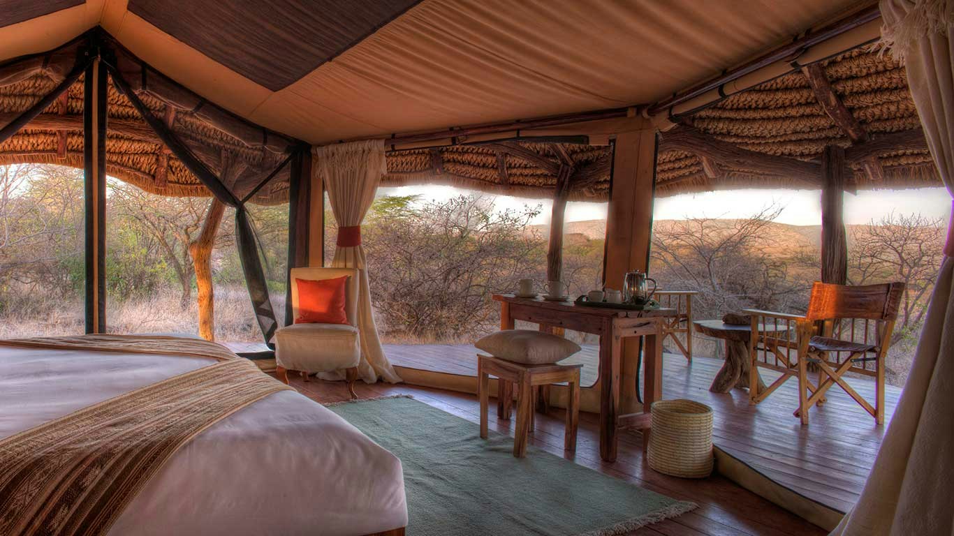 Guest tent with a bed and seating by the veranda at Lewa Safari Camp