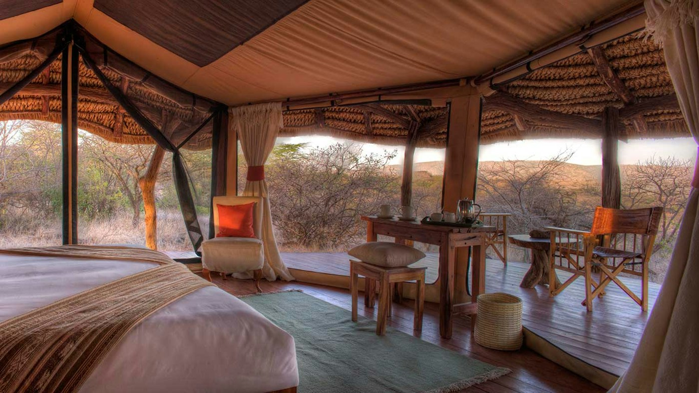 Guest tent with a bed and seating by the veranda at Lewa Safari Camp