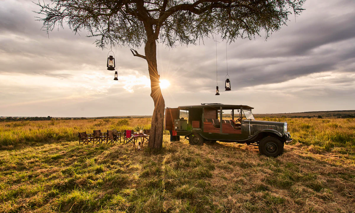 A private safari picnic beside a vehicle at sunset