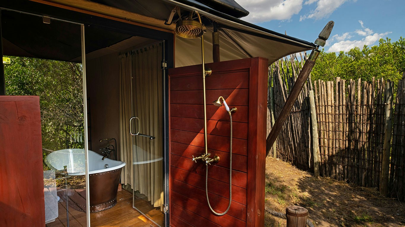 Private outdoor shower beside a guest tent at Sand River Mara