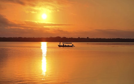 Sunset over lake with boat on river at Selous Game Reserve, Tanzania