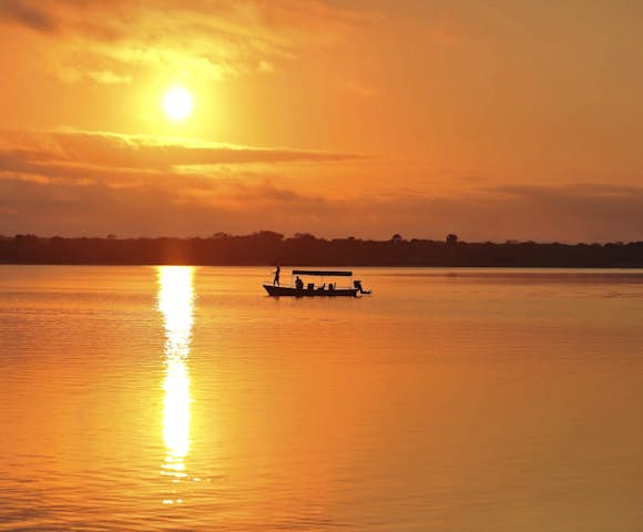 Sunset over lake with boat on river at Selous Game Reserve, Tanzania