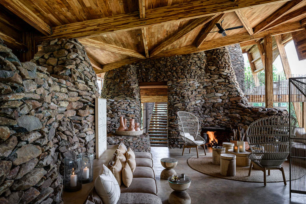 The stone-and-timber lounge with an open fire at Singita Faru Faru Lodge, Serengeti, Tanzania