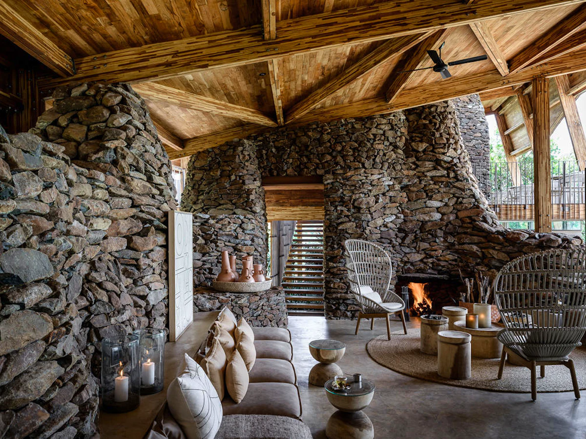 The stone-and-timber lounge with open fire at Singita Faru Faru Lodge, Serengeti, Tanzania