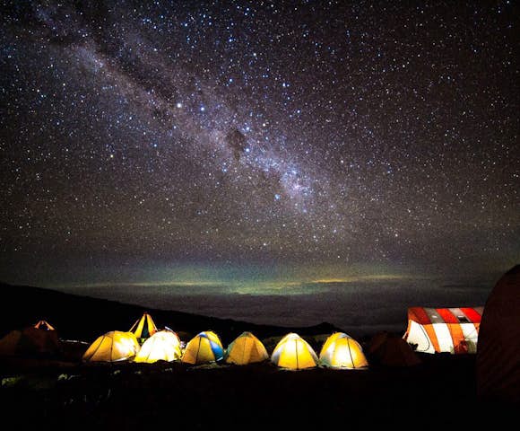 Night sky above glowing tents on Kilimanjaro hike in Tanzania